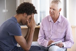 a young man talking to his doctor about mental health treatment