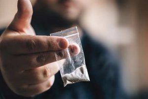 person holding out a baggy needing cocaine addiction treatment