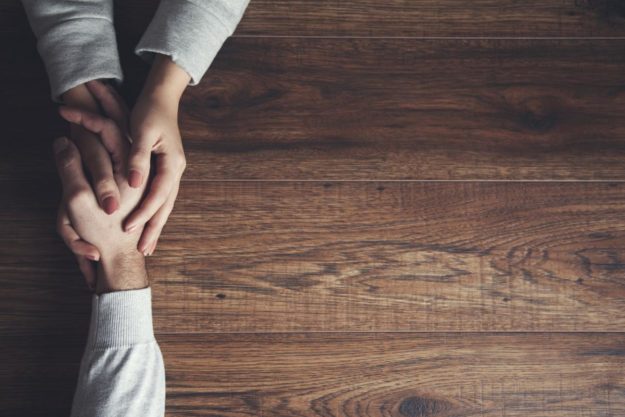 hand holding across table showing the benefits of trauma informed therapy
